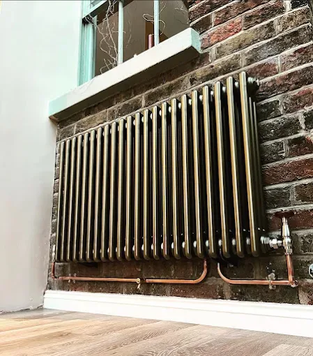 Column radiator mounted on exposed brick with new copper feeds