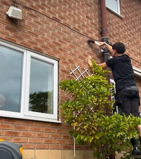 Plumber on a ladder repairing an exterior soil stack connection